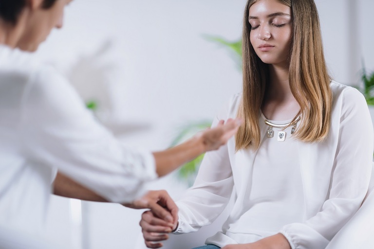 Private Session

Pavitram Healing healing therapist performing alternative therapy treatment with young woman patient. Peaceful teenage girl sitting with her eyes closed. Therapist doing applied and muscle testing by holding hands. Wearing white clothes.